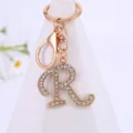 Closeup of sparkling rhinestone letter R keychain with gold alloy ring for stylish bag decoration. - Letter R