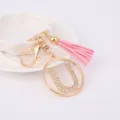 Gold rhinestone letter U keychain with pink tassel charm, detailed metal bag accessory. - Letter U