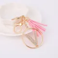 Metal rhinestone letter V keychain with pink tassel charm, elegant bag accessory detail view. - Letter V