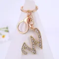 Gold rhinestone letter keychain close-up detail, sparkling crystal alphabet pendant hardware. - Letter W