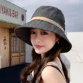 Detailed close-up view of the stylish dark grey bucket hat worn by a model outdoors. - Black