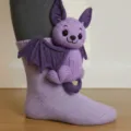 Niedliche handgefertigte 3D-Stricksocken mit dekorativem lila Fledermaus-Plüschtier. - Fledermaus
