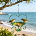 Macro view of heart-shaped iron bird feeder hanging on a beach with wild birds - Dark Green