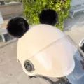 Detailansicht süßer schwarzer flauschiger Bommelohren auf beiger Motorradhelm mit Visier. - Schwarzer Pelzball