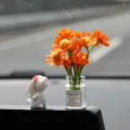 Cute car dashboard ornament featuring a white rabbit and mini vase with orange flowers. - Sniffing Rabbit + Orange Daisy Vase