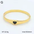 Gros plan d'un bracelet manchette en acier inoxydable doré avec un insert cœur noir élégant. - Style 10