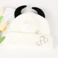 White knit beanie hat with black devil horns, distressed holes, and metal ring pins details. - Adjustable / White Black