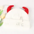 Close up of white knitted beanie with red devil horns and metal safety pins detail. - Adjustable / White and Red