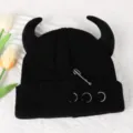 Black knitted beanie with devil horns, metal safety pin, and ring decor. Detail view. - Adjustable / Black