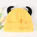 Yellow knitted beanie detail showing black devil horns, safety pin, and ring piercing decors. - Adjustable / Yellow