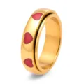 Detaillierte Makroansicht eines goldenen Titan-Spinnerrings mit roten Emaille-Herzen. - Gold Rot