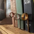 Primo piano di tre segnalibri a spirale in rame, argento e oro su libri antichi - Pezzo Singolo / Argento