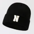Black knit beanie for men and women, featuring a stylish white letter N patch with gold edge. - Adjustable / Letter N
