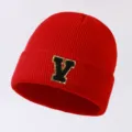 Red knit beanie with a stylish gold-bordered letter V patch for autumn and winter outdoor warmth. - Letter V