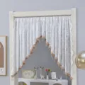 Detailed view of the French pastoral white lace arched half curtain with gold trim and tassels. - Starlight White Pole Sold Separately
