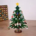 Miniatur Weihnachtsbaum aus grünem Holz mit bunten festlichen Ornamenten auf dem Tisch - M / Grün
