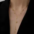 Detailansicht einer goldenen Y-Halskette mit Perlen vor einem schwarzen Hintergrund - Perlenquasten-Stil (H202) / Gold