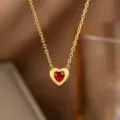 Nahaufnahme einer goldenen Herz-Halskette mit einem leuchtend roten herzförmigen Edelstein - Rote Strass Herz Halskette (H1220) / Gold/Rot