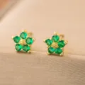 Detaillierte Makroansicht von goldfarbenen Blumenohrringen mit leuchtend grünen Zirkonia-Blüten - Grüner Zirkonia Blumenstil (7051) / Ohrstecker / Gold