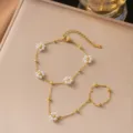 Detail eines goldenen Handketten-Armbands aus Edelstahl mit Perlenblumen-Charms. - Fünf Perlenblumen Handkette (Gold)
