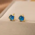 Nahaufnahme von eleganten goldenen Ohrsteckern mit blauen Steinen auf einer Schmuckschatulle. - Blauer Zirkonia Solitär Stil (7055)