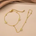 Detailansicht einer goldenen Handkette aus Edelstahl mit zarten grünen Blumenanhängern. - Cyan Blume Handkette (Gold)