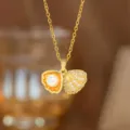 Nahaufnahme einer goldenen Muschelkette mit Perle und funkelnden Zirkonia-Steinen - Perlen-Muschel-Halskette (8119) / Gold