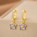 Nahaufnahme eleganter Goldohrringe mit lila Zirkonia-Blumenanhängern und Kristallen. - Lila Zirkonia Blumenstil (7056)