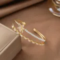 Detailansicht eines vergoldeten Blumen-Armreifs mit funkelnden Zirkoniasteinen im Makrofokus - Doppellagiges Weißes Strass Ahornblatt (E2909) / Gold