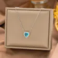 Elegante Halskette mit herzförmigem Aquamarin-Anhänger auf einer beigen Schmuckschatulle - Nur Halskette (7009) / Hellblaues Herz (Silber)