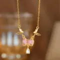 Detailaufnahme einer zarten Halskette mit rosa Schleife und glitzerndem Zirkon - Rosa Muschel Schleife (9128) / Gold