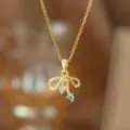 Detaillierte Nahaufnahme einer goldenen Schleifenkette mit herzförmigen blauen Edelsteinen - Blaue Zirkonia Herz Schleife Halskette (9417)