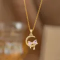 Nahaufnahme einer goldenen Mondhalskette mit einem rosa Kristall-Schleifenanhänger - Rosa Zirkonia Schmetterling Mond Halskette (9413)