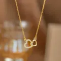 Detailansicht einer goldfarbenen Halskette mit zwei verschlungenen Herzen und Kristallen. - Große und Kleine Herzen Doppelring (9403)