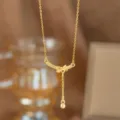 Detaillierte Nahaufnahme einer eleganten goldenen Halskette mit Schleifenanhänger und Perle - Lächeln Schleife Quaste (9405)