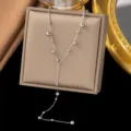 Elegante silberfarbene Y-Halskette mit polierten Perlenakzenten auf einem Display - Perlenquasten-Stil (H234) / Stahlfarben