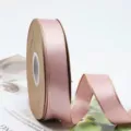 Gros plan sur le rouleau de ruban de satin rose avec des bords dores pour la decoration. - Taille 25 / Rose Poudré
