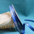 Closeup of blue grosgrain ribbon with gold stamped love text, perfect for gift box packaging. - 1.0cm Width / 40 Yards / Navy Blue