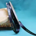 Closeup view of dark blue grosgrain ribbon with gold foil LOVE IS ETERNAL text detail. - 1.0cm Width / 40 Yards / Black