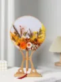 Vista dettagliata di ventaglio rotondo in fiori secchi stile cinese con supporto in legno. - Kit materiale ventaglio tondo giallo-arancio con supporto di corte in resina