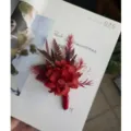 Red preserved flower wedding boutonniere detail shot, elegant romantic floral accessory for groom. - Red Gold Corsage
