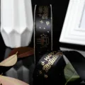 Close-up of black satin ribbon with gold happy birthday print, cake pattern, decorative. - Black
