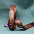 Cinta acanalada marrón con texto dorado impreso, ideal para envolver flores y regalos. - Café
