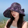 Vista detallada de un elegante sombrero de sol floral morado usado al aire libre junto al mar. - Púrpura