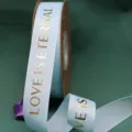 Light blue grosgrain ribbon with gold foil LOVE IS ETERNAL print, ideal for bouquet gift wrapping. - Light Blue