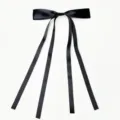 Close up of black satin ribbon hair bow with long streamers, elegant hair accessory detail. - Black