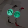 Vue détaillée des charmes de lune lumineux vert sur des bracelets de couple rouges et noirs - Style Lumineux Lune