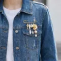 Close-up of a gold seashell and pearl charm brooch pinned to a blue denim jacket. - Ocean Starfish Fish Style (26Y0002)