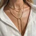 Detailed macro shot of a gold-colored Y-shaped multi-layered necklace with a sun pendant. - Gold Sun Pendant Style (XK26Y0295)