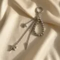 Dettaglio di un ciondolo borsa argento con stelle e perle metalliche su sfondo di seta - Stile Cono Stella Multistrato Argento (XK26Y0518)